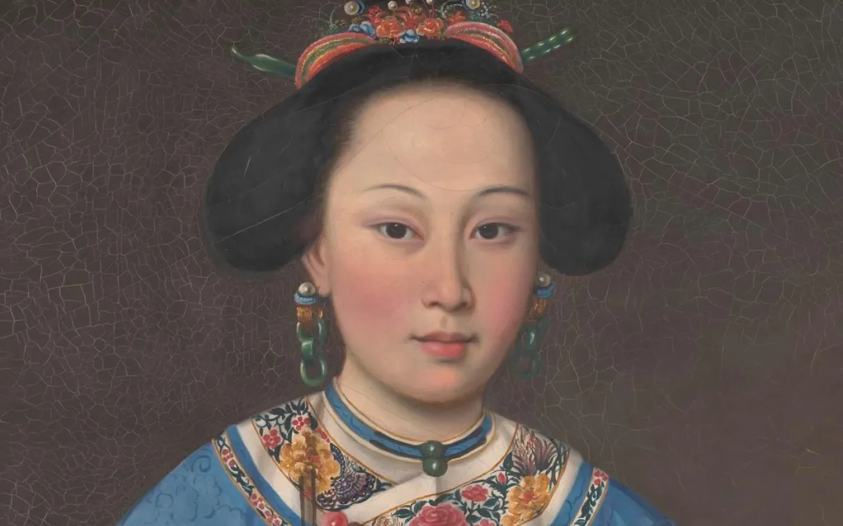 Portrait of an Asian woman wearing traditional blue embroidered clothing, elaborate hair ornaments, earrings, and a choker necklace.