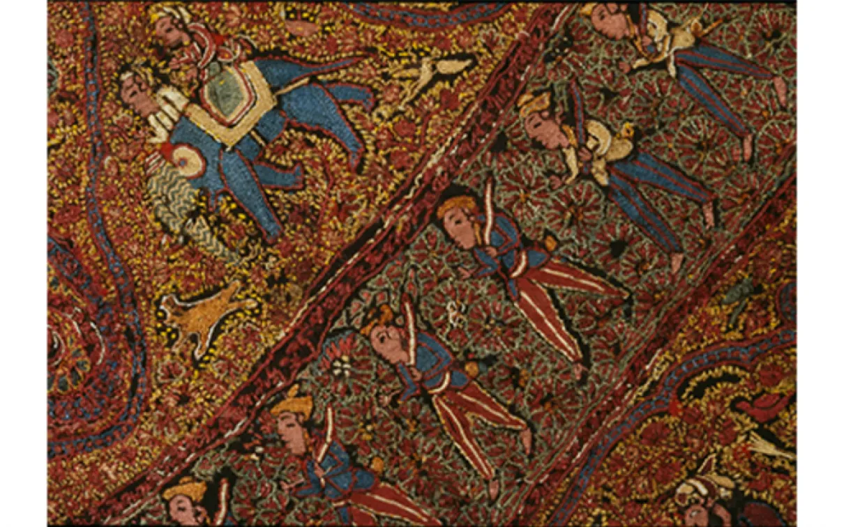 Colorful textile with intricate patterns depicting human figures, elephants, and floral motifs on a reddish-brown background.