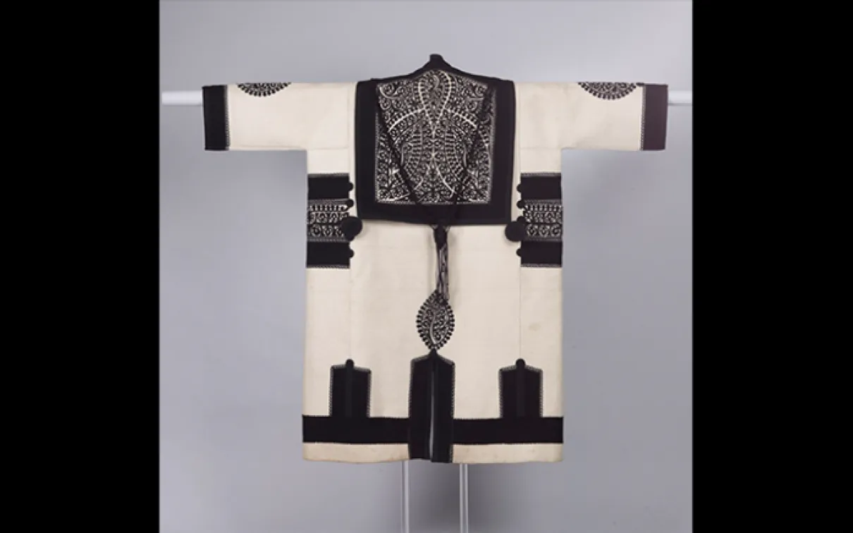Man's szür (mantle). Made in present-day Romania in the Transylvanian Hungarian tradition. c. 1900. Fulled white woollen material trimmed with applied bands of black broadcloth and cutout patterns of black felt; trimming enriched with small black knotted roundels. 970.227.9 Gift of the Hungarian Helikon Society, 1973.
