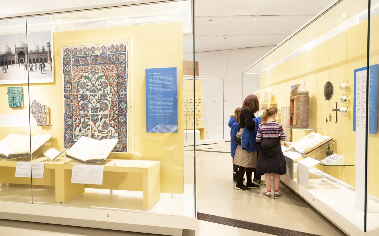 A family examines a Middle Eastern artifact in a gallery case.