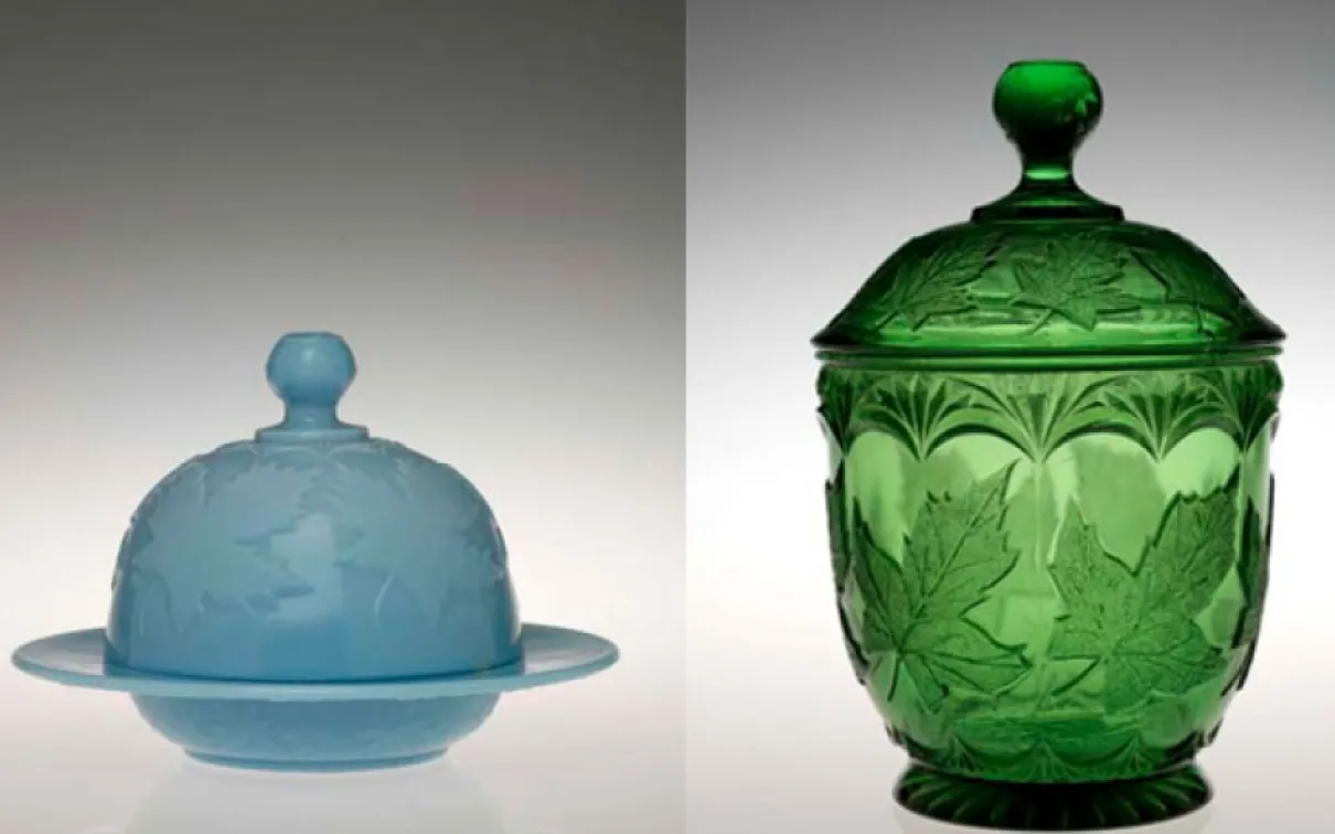 Two glass containers, one blue with a dome-shaped lid and base, the other green with a tall, ornate lid and textured pattern.