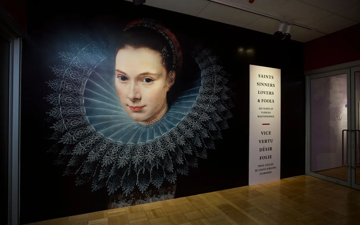 Mural of a woman with a lace ruff collar next to a vertical text panel listing names and dates.