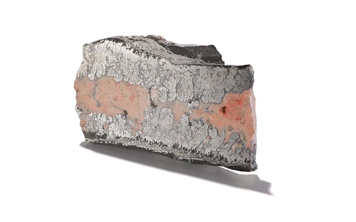 Pie-shaped sample of cobalt mineral encased in smaltite, shown on a white background.