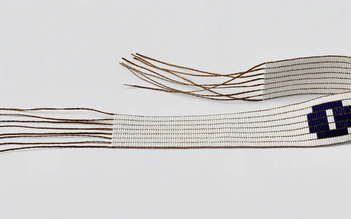 A white beaded belt with a purple circle on it