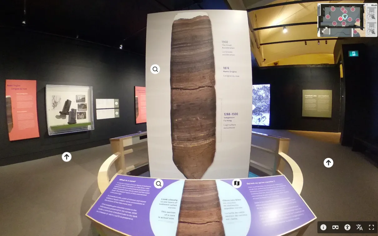 A display in the centre of a museum gallery with dark walls shows a core sample with layers of deposits in various shades of brown and black.