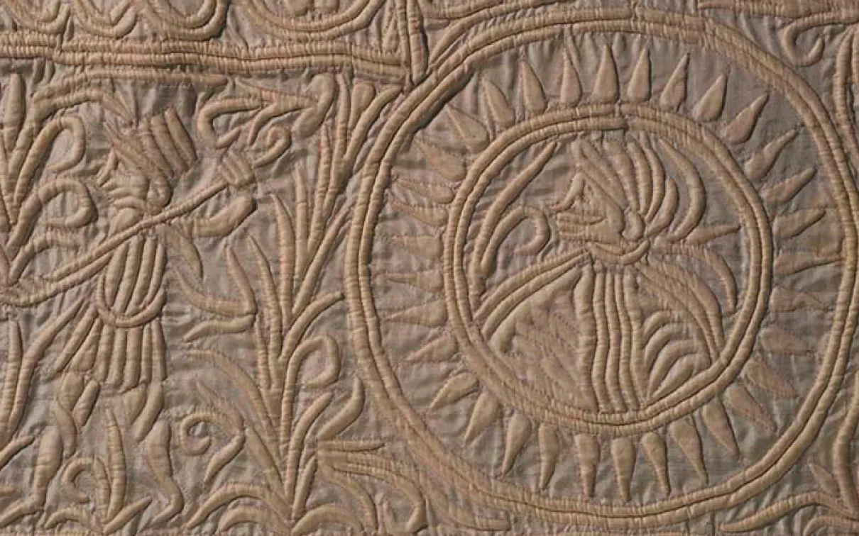 Intricate leaf and flower patterns carved in circular and curved designs on a textured stone surface.