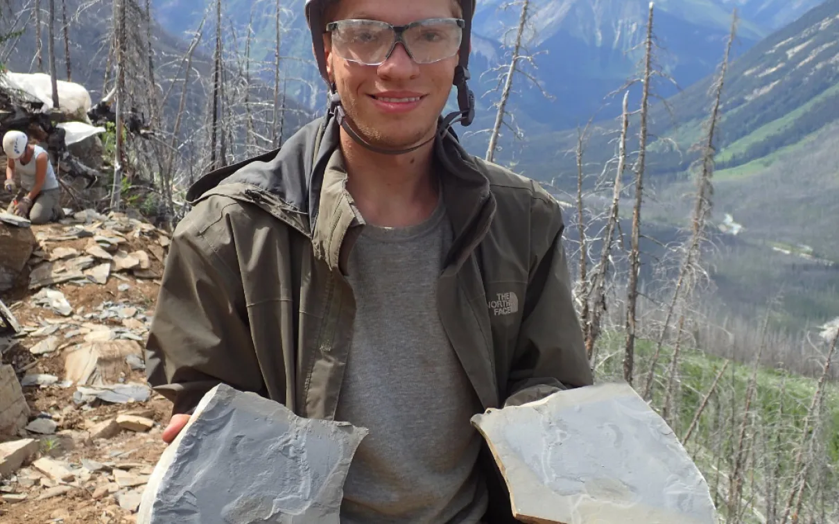 Student holding shale slabs with fossils.
