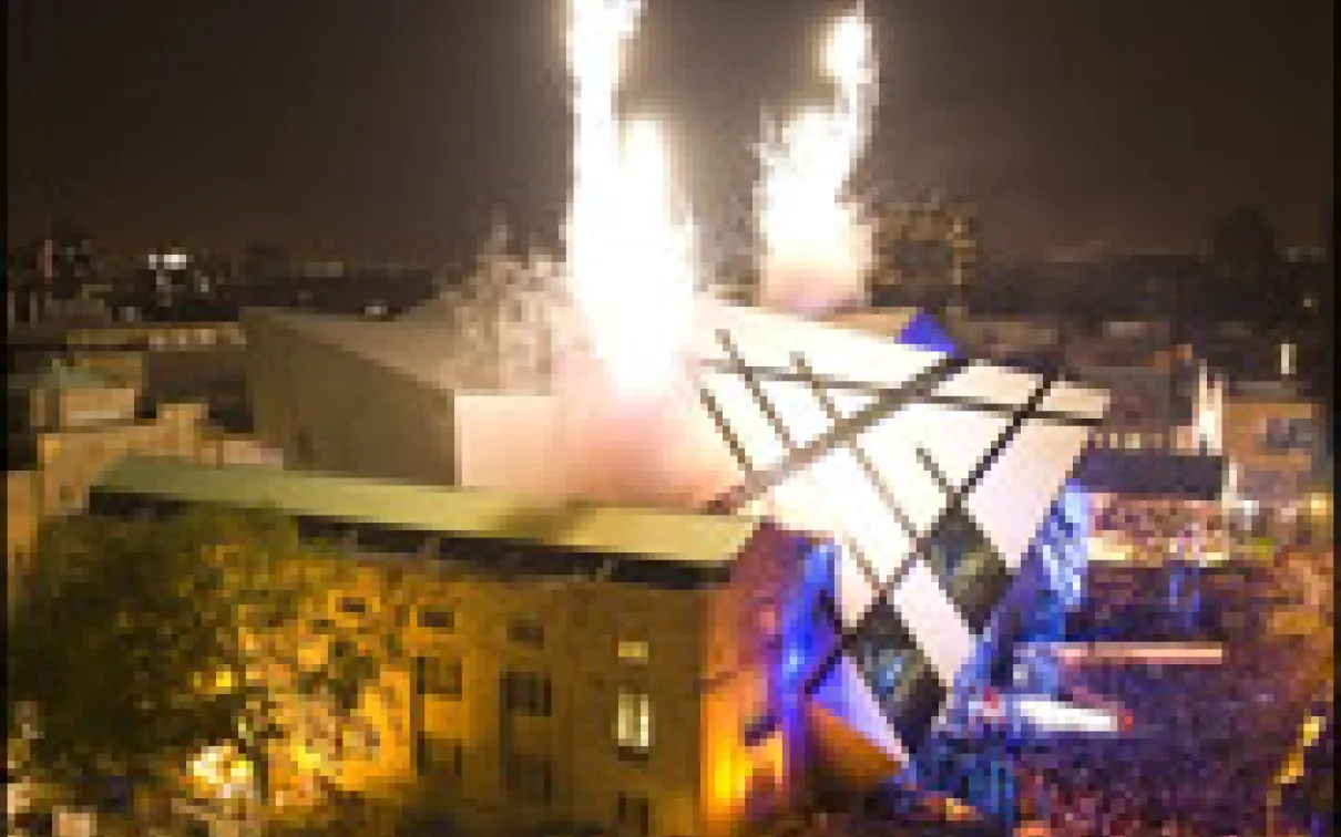 Nighttime view of the illuminated Royal Ontario Museum Michael Lee-Chin Crystal extension with fireworks overhead and a crowd below.