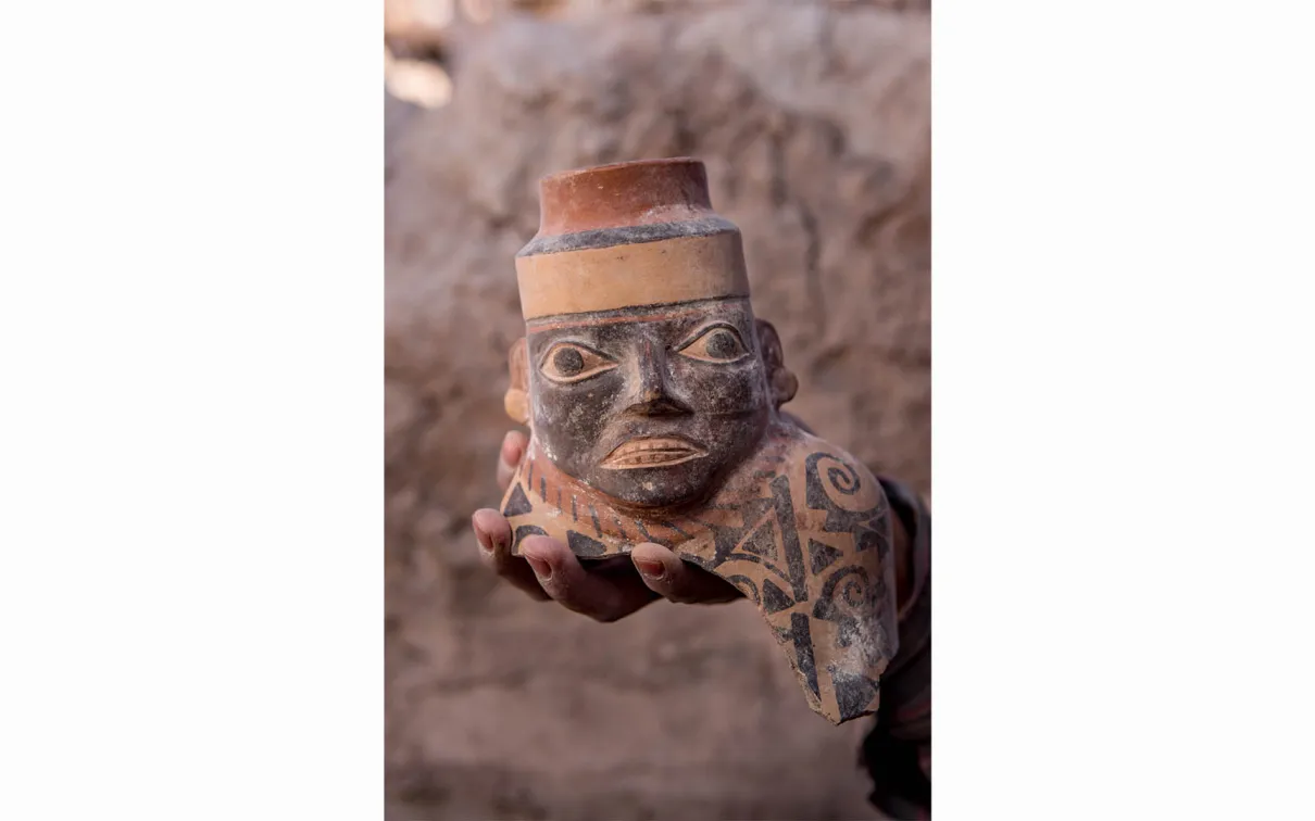 Gros plan d'une jarre à col facial. Plus de 800 ans avant les Incas, l'État Wari s'est étendu hors de la Sierra centrale péruvienne vers 600 après J.-C. et a façonné les interactions dans la région pendant les quatre cents années suivantes. Les céramiques Wari, comme cette jarre à col facial de Robles Moqo découverte à Quilcapampa, se retrouvent dans une grande partie du Pérou.
