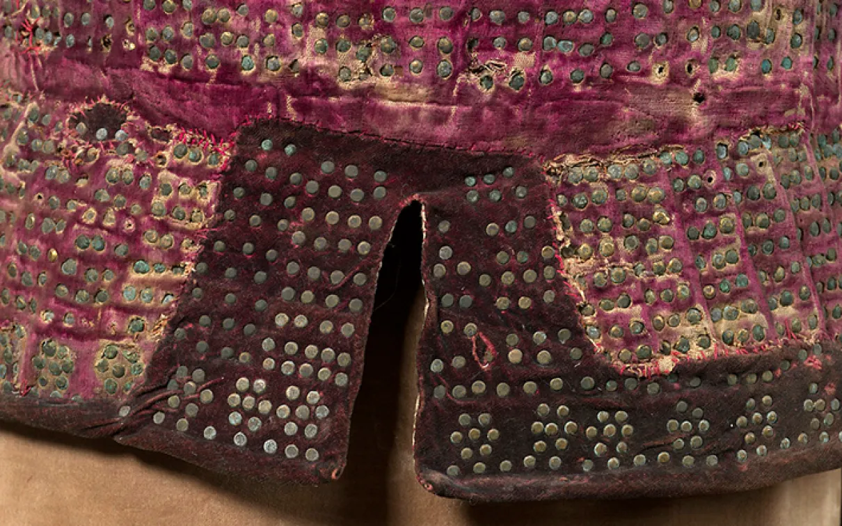 Close-up of fabric decorated with a grid of small metal studs on a red textile background.
