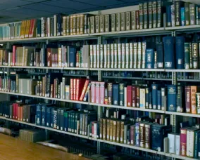 Rows of shelves filled with various hardcover books in a library setting.