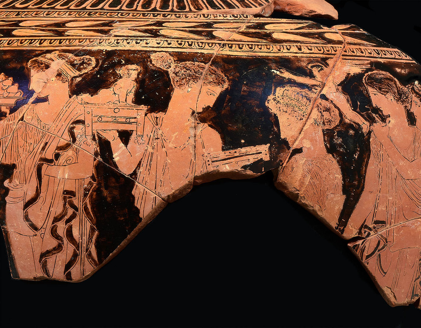 Fragment of a red-figure Greek vase showing three draped human figures, with one holding a staff or spear.